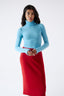 Model wearing a sky blue merino wool turtleneck bodysuit and a red merino skirt