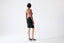 Model wearing a black merino pencil skirt on a white background, back view
