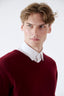 Close-up of model wearing burgundy cashmere V-neck jumper with white shirt by Roksolana.