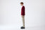 Model wearing burgundy cashmere V-neck jumper with beige trousers, side view.