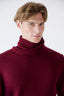 Close-up of model wearing burgundy merino wool turtleneck jumper.