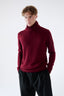 Model wearing burgundy merino wool turtleneck jumper, front view.