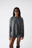 Woman wearing a grey jumper and shorts on a white background