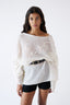 Model wearing ivory mohair wool-blend oversized poncho with black mini skirt and boots, front view.