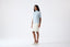 Model wearing light blue merino wool short-sleeve turtleneck jumper, side view.