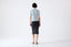 Model wearing light blue merino wool short-sleeve turtleneck jumper, back view.