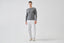 Model wearing melange grey merino-cashmere blend jumper with white trousers, front view.