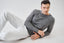 Model wearing melange grey merino-cashmere blend jumper with white trousers.