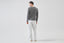 Model wearing melange grey merino-cashmere blend jumper with white trousers, back view.