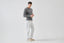 Model wearing melange grey merino-cashmere blend jumper with white trousers, side view.