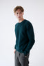 Model wearing a dark green merino jumper, side view