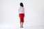 Model wearing pink merino wool turtleneck jumper with red skirt, back view.