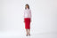 Model wearing pink merino wool turtleneck jumper with red skirt, front view.