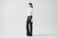 Model wearing black sheer mohair-alpaca knit trousers with white bodysuit, side view.