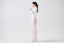 Model wearing white sheer mohair-alpaca knit maxi skirt with white top, side view.