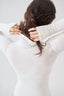 Model wearing a white merino wool long-sleeve bodysuit, back view.