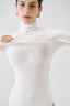 Model wearing a white merino wool long-sleeve turtleneck bodysuit, front view.