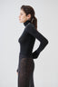 Woman wearing a black merino bodysuit, side view