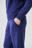 Close-up of cobalt blue merino wool-blend knitted trousers showing pocket and ribbed waistband detail.