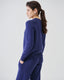 Model wearing cobalt blue merino wool-blend crew neck jumper with matching trousers, side view.