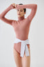 Model wearing a warm brown merino bodysuit on a white background