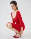 Model wearing a red wool skirt and cardigan on a white background