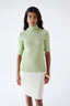 Model wearing a light green wool short-sleeve turtleneck jumper by Roksolana.