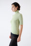 Model wearing a light green wool short-sleeve turtleneck jumper by Roksolana, side view